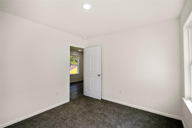 empty room featuring dark colored carpet, baseboards, and recessed lighting