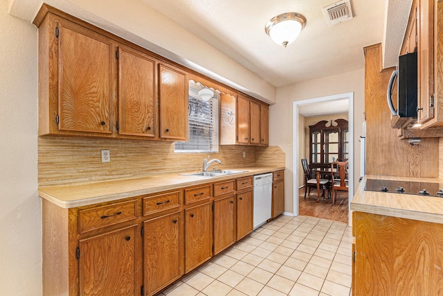 19331 E Lakeshore Dr, Magnolia, TX 77355 - kitchen featuring white dishwasher, a sink, stainless steel microwave, light countertops, and decorative backsplash