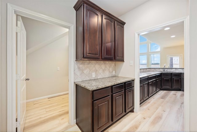 kitchen with decorative backsplash, dark brown cabinets, and light wood finished floors