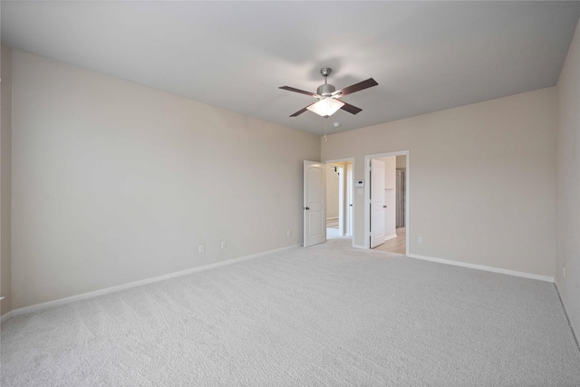 unfurnished bedroom featuring light carpet, connected bathroom, a ceiling fan, and baseboards