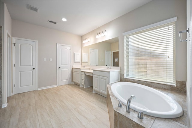 bathroom featuring double vanity, a bath, and visible vents