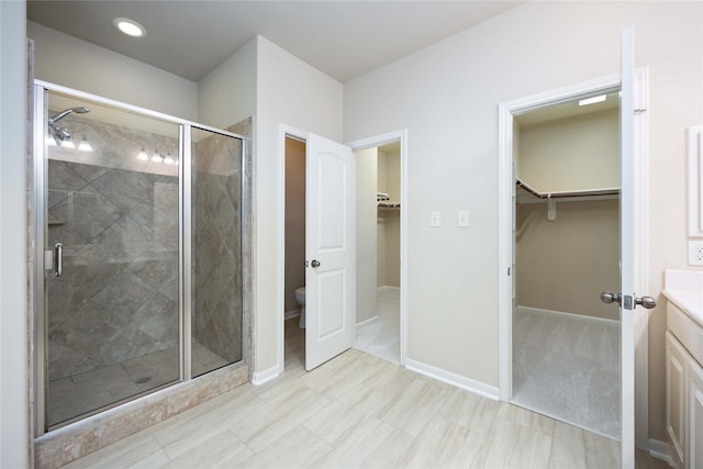 full bath with vanity, toilet, baseboards, and a stall shower