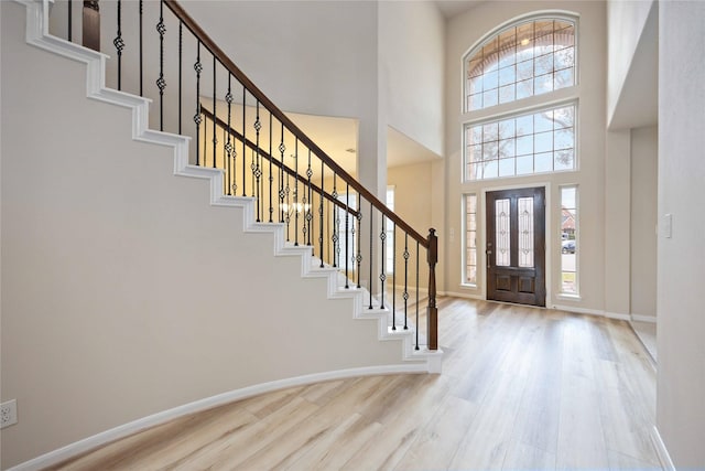 entryway with stairway, a high ceiling, baseboards, and wood finished floors