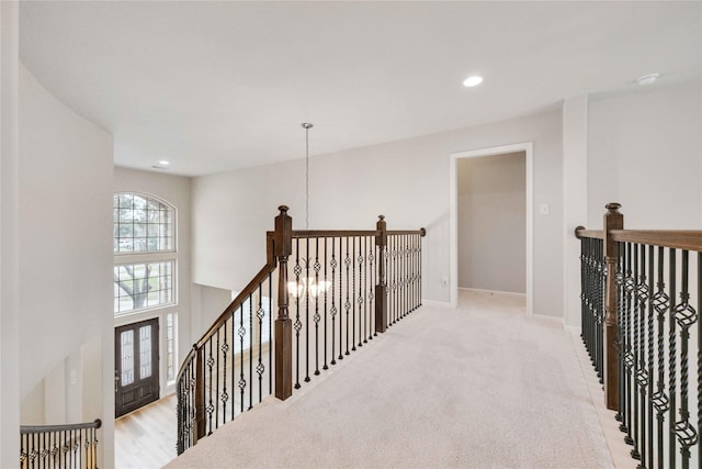 hallway featuring carpet, baseboards, recessed lighting, an upstairs landing, and a chandelier