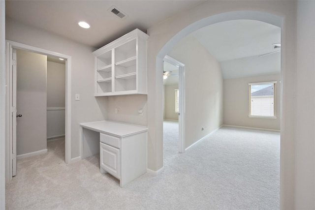 interior space featuring light colored carpet, visible vents, arched walkways, and baseboards