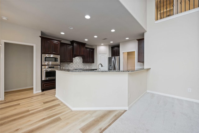 kitchen with light stone counters, stainless steel appliances, decorative backsplash, baseboards, and dark brown cabinets