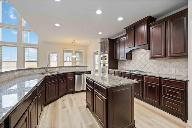 kitchen with backsplash, light wood-type flooring, appliances with stainless steel finishes, and a sink