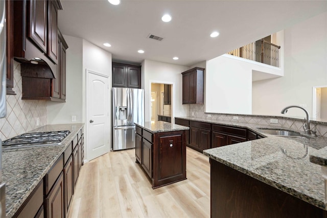 kitchen featuring light stone counters, visible vents, a sink, appliances with stainless steel finishes, and light wood-type flooring