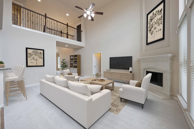 living area featuring a wealth of natural light, light colored carpet, ceiling fan, and a fireplace