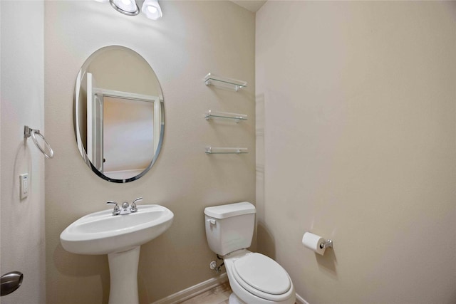 half bathroom with baseboards and toilet