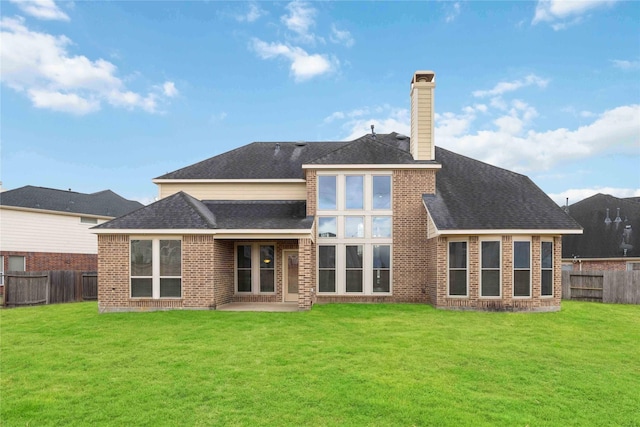 back of property featuring brick siding, a shingled roof, a chimney, a fenced backyard, and a yard