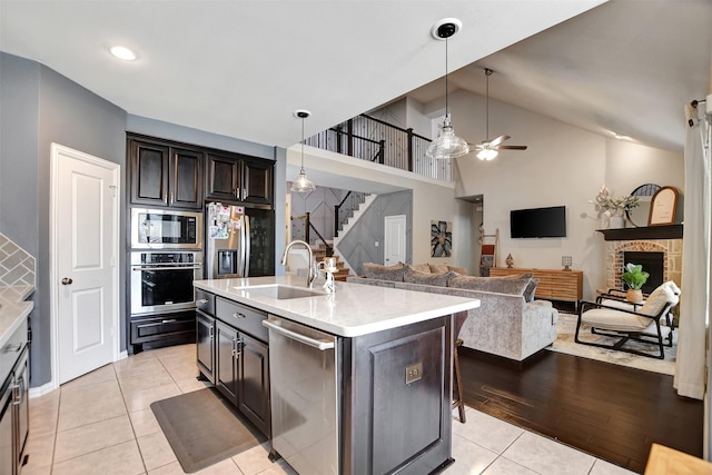 kitchen with light tile patterned floors, a sink, stainless steel appliances, light countertops, and open floor plan