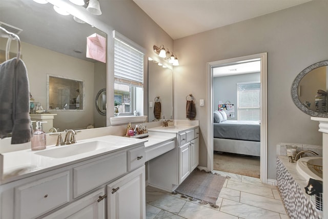 ensuite bathroom with visible vents, double vanity, a sink, a bath, and marble finish floor