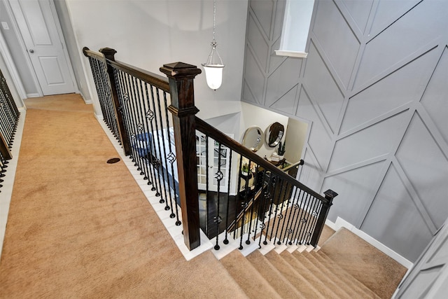 stairway featuring a decorative wall and carpet