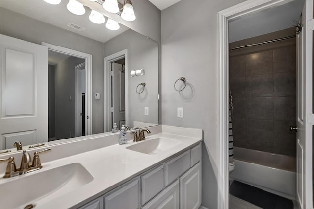 bathroom featuring double vanity, toilet, visible vents, and a sink