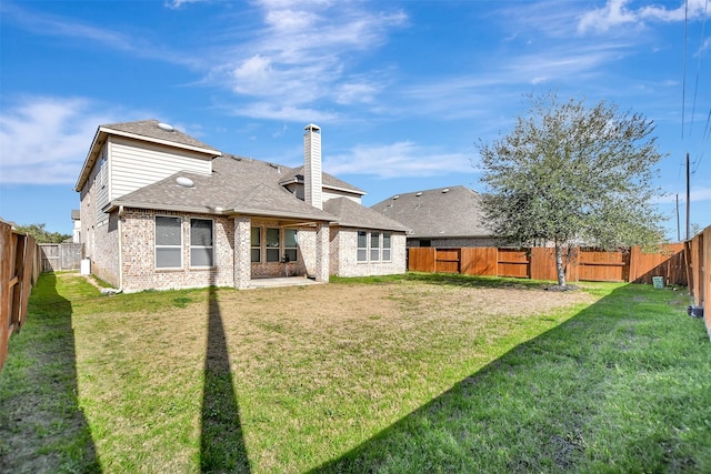 back of house with brick siding, a lawn, a chimney, and a fenced backyard