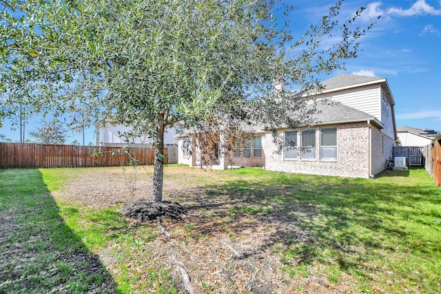 back of property with brick siding, a lawn, a shingled roof, and a fenced backyard