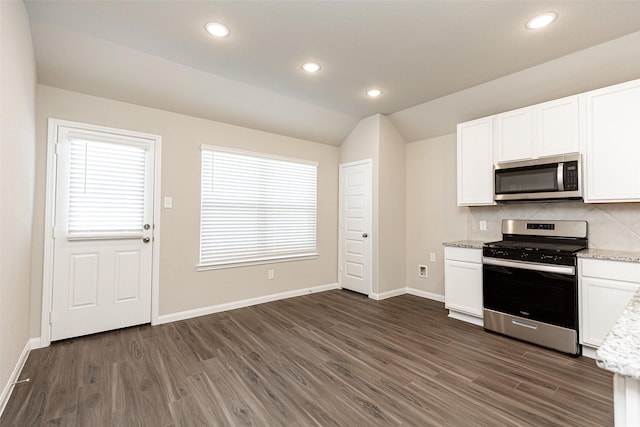 kitchen with light stone counters, dark wood-style flooring, stainless steel appliances, vaulted ceiling, and backsplash