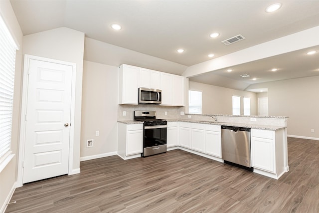 kitchen featuring visible vents, lofted ceiling, appliances with stainless steel finishes, a peninsula, and white cabinets