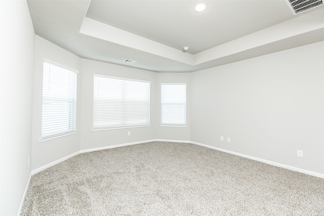 unfurnished room featuring a tray ceiling, baseboards, and visible vents