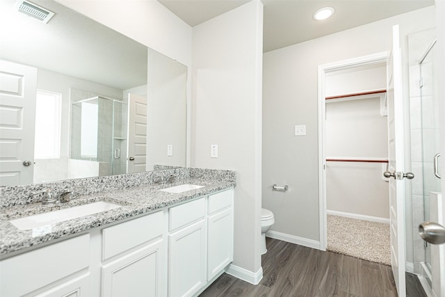 bathroom with a walk in closet, a shower stall, visible vents, and a sink