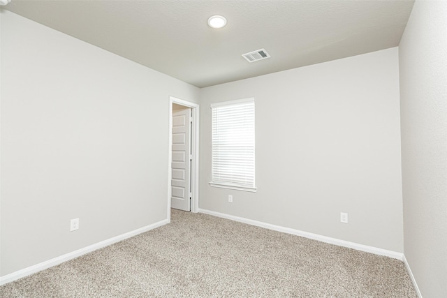 unfurnished room with visible vents, baseboards, and light colored carpet