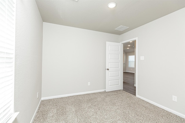 carpeted empty room featuring visible vents and baseboards