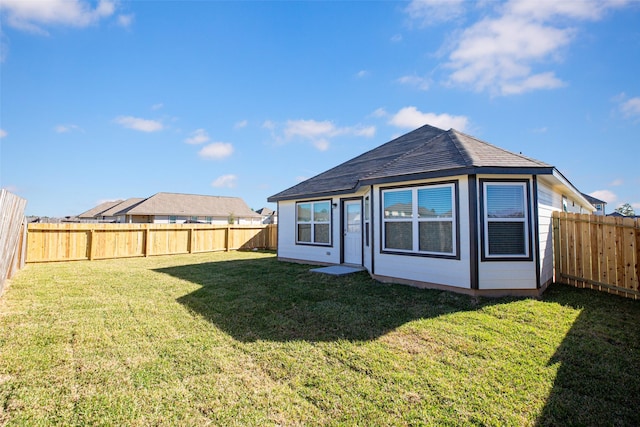 rear view of house featuring a yard and a fenced backyard