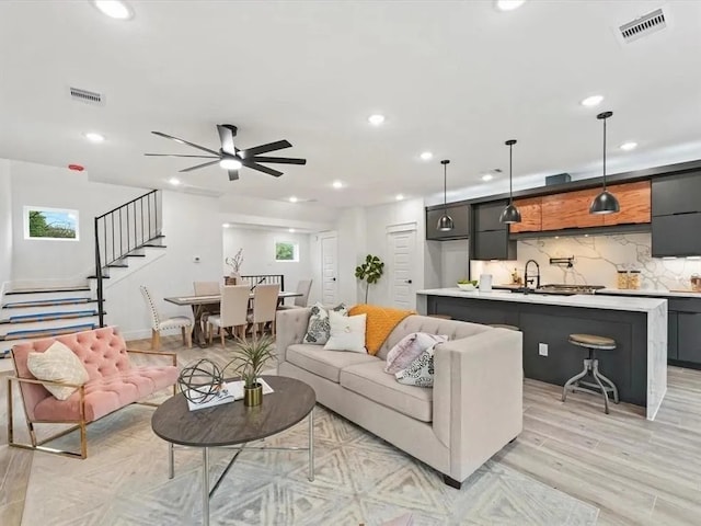 living room featuring recessed lighting, visible vents, light wood-type flooring, and stairs