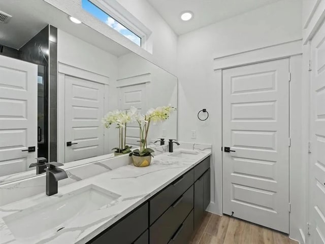 bathroom featuring a sink, visible vents, wood finished floors, and double vanity