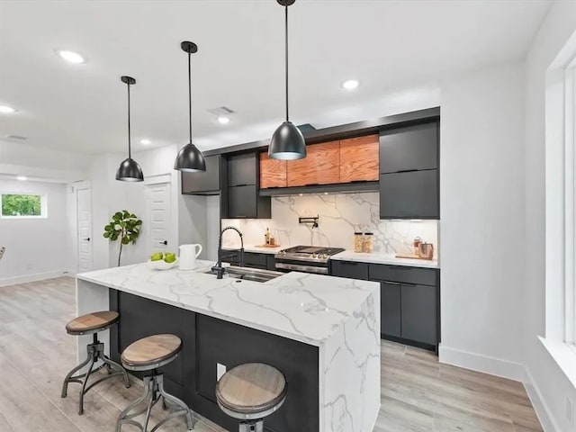 kitchen featuring a breakfast bar area, gas stove, a sink, modern cabinets, and backsplash