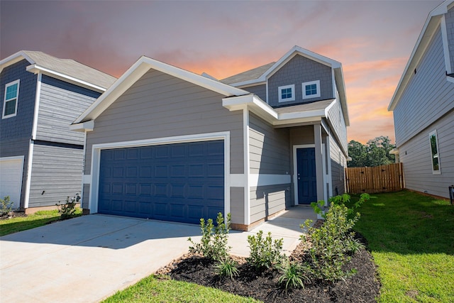 view of front facade featuring a yard, concrete driveway, a garage, and fence