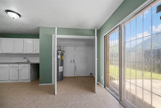 interior space featuring washer hookup, water heater, laundry area, light tile patterned flooring, and a sink