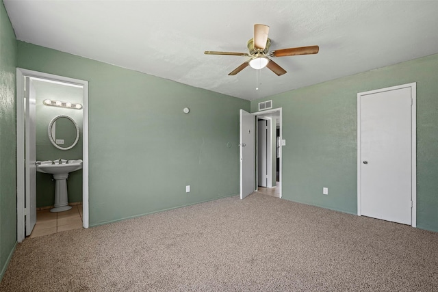 unfurnished bedroom with ensuite bath, a ceiling fan, visible vents, and carpet floors