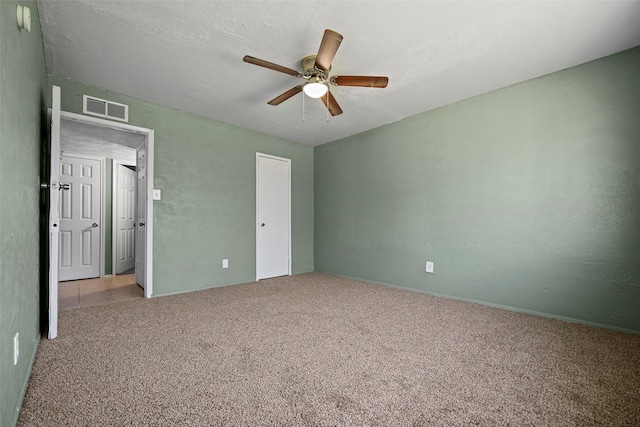 unfurnished bedroom featuring visible vents, ceiling fan, carpet, a textured wall, and a textured ceiling