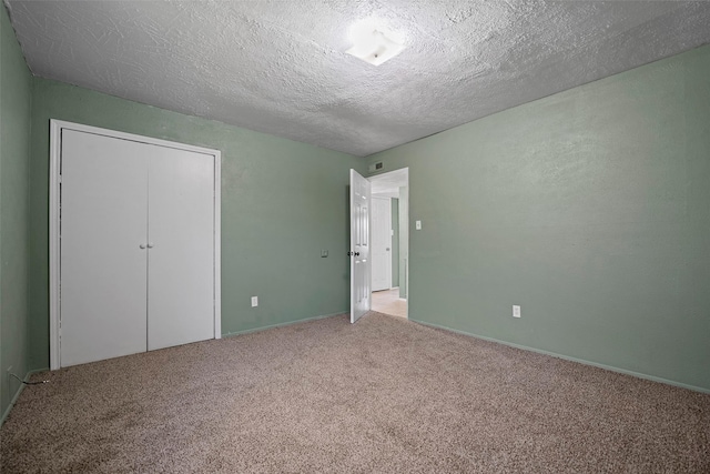 unfurnished bedroom featuring a closet, light colored carpet, and a textured ceiling