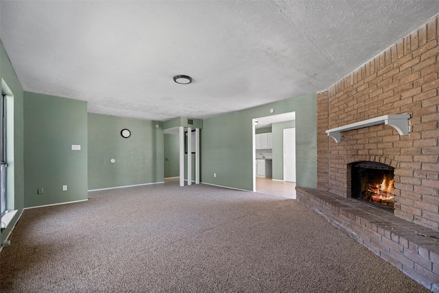 unfurnished living room with baseboards, carpet, a brick fireplace, and a textured ceiling