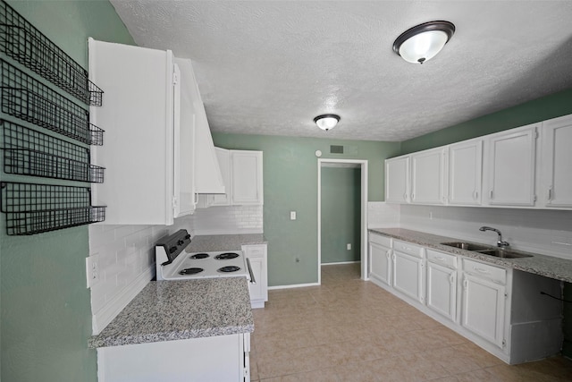 kitchen featuring electric range, visible vents, a sink, backsplash, and white cabinetry