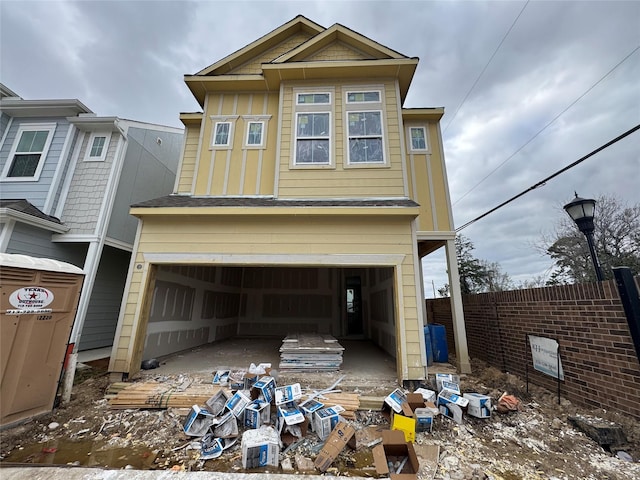 view of front facade featuring board and batten siding, a garage, and fence