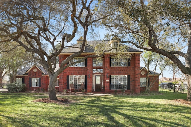 colonial home with brick siding, a front lawn, and fence