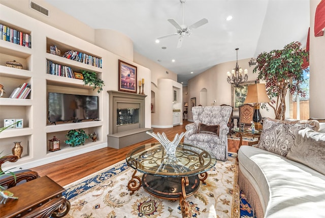 living area with built in features, wood finished floors, visible vents, recessed lighting, and ceiling fan with notable chandelier