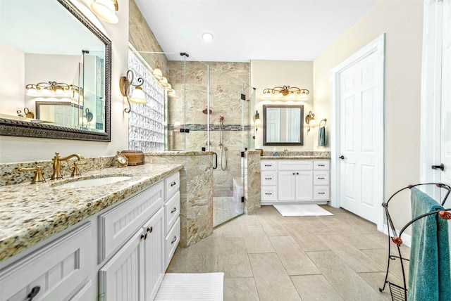 bathroom featuring a shower stall, two vanities, and a sink