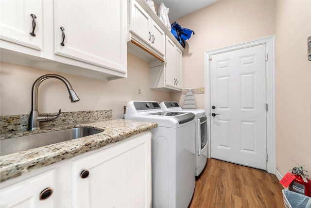 washroom featuring a sink, cabinet space, light wood-style flooring, and washer and clothes dryer