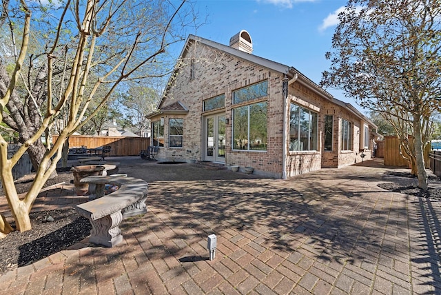 rear view of house with a patio, french doors, a fenced backyard, and a chimney