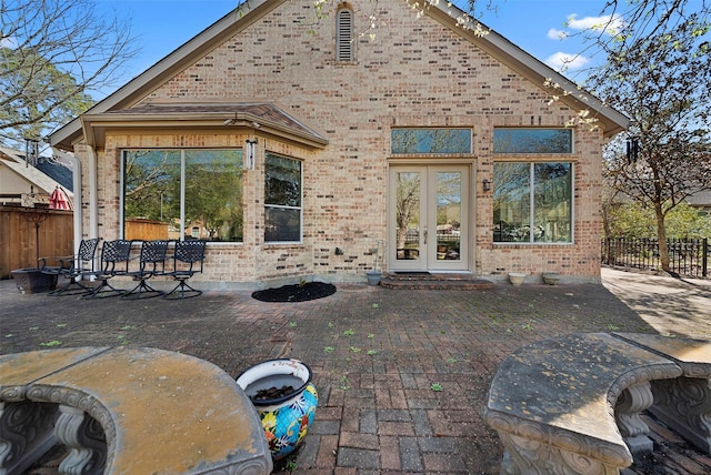 back of property featuring french doors, a patio, brick siding, and fence