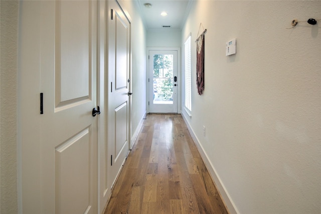 corridor featuring wood finished floors, visible vents, and baseboards