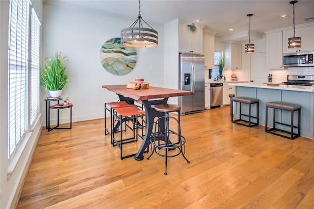 dining area featuring recessed lighting, light wood-style flooring, crown molding, and baseboards