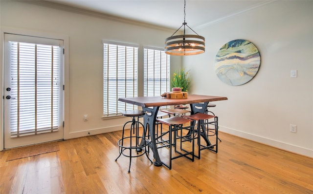 dining room with a chandelier, light wood-style flooring, baseboards, and ornamental molding