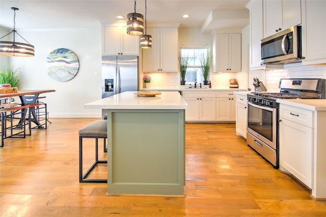 kitchen with a center island, a breakfast bar, baseboards, appliances with stainless steel finishes, and recessed lighting