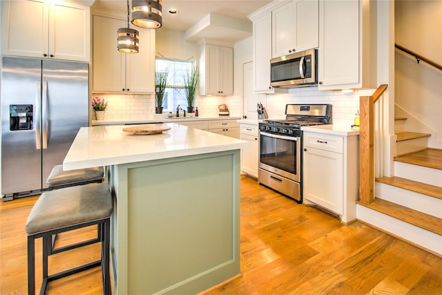 kitchen featuring a center island, a kitchen breakfast bar, a sink, stainless steel appliances, and light countertops